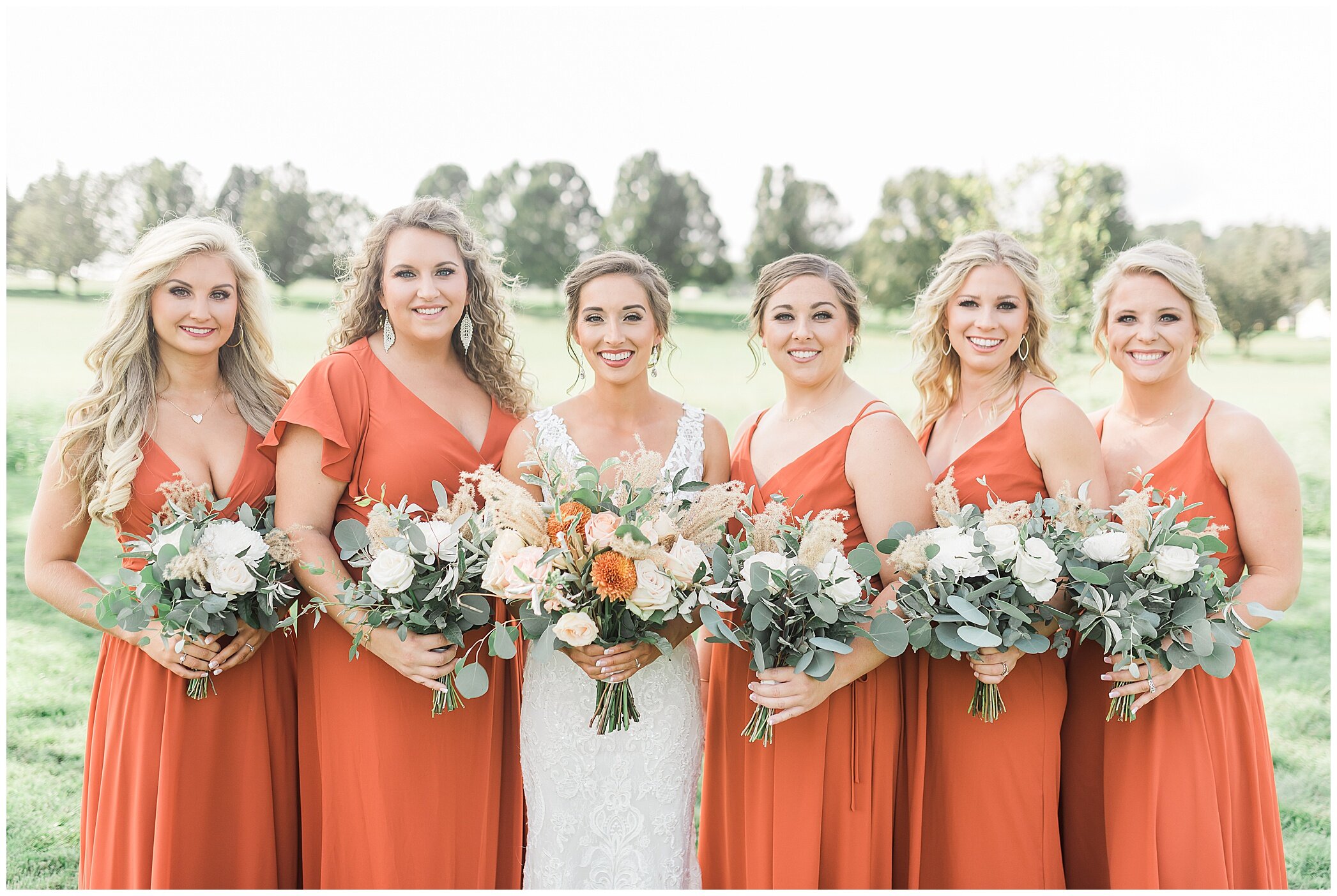 bride poses with 5 bridesmaids in orange gowns
