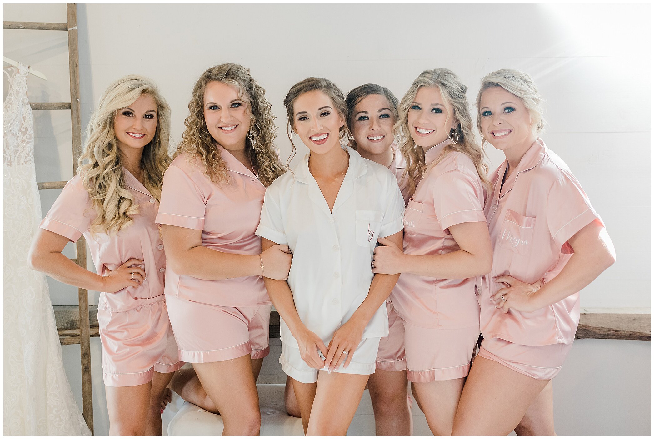bride poses with bridesmaids in matching pink pjs
