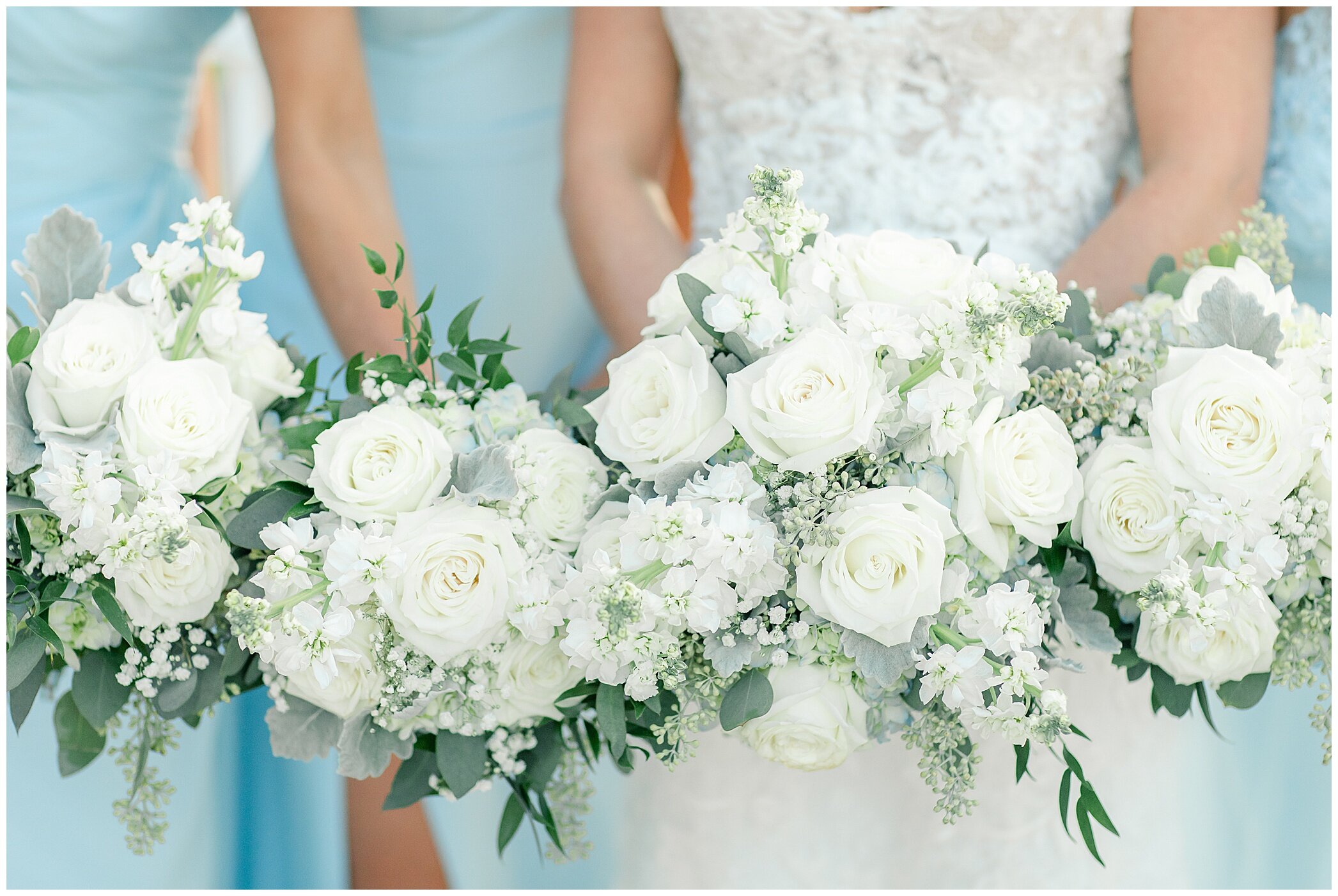 bridesmaids in pastel blue gowns hold white bouquets