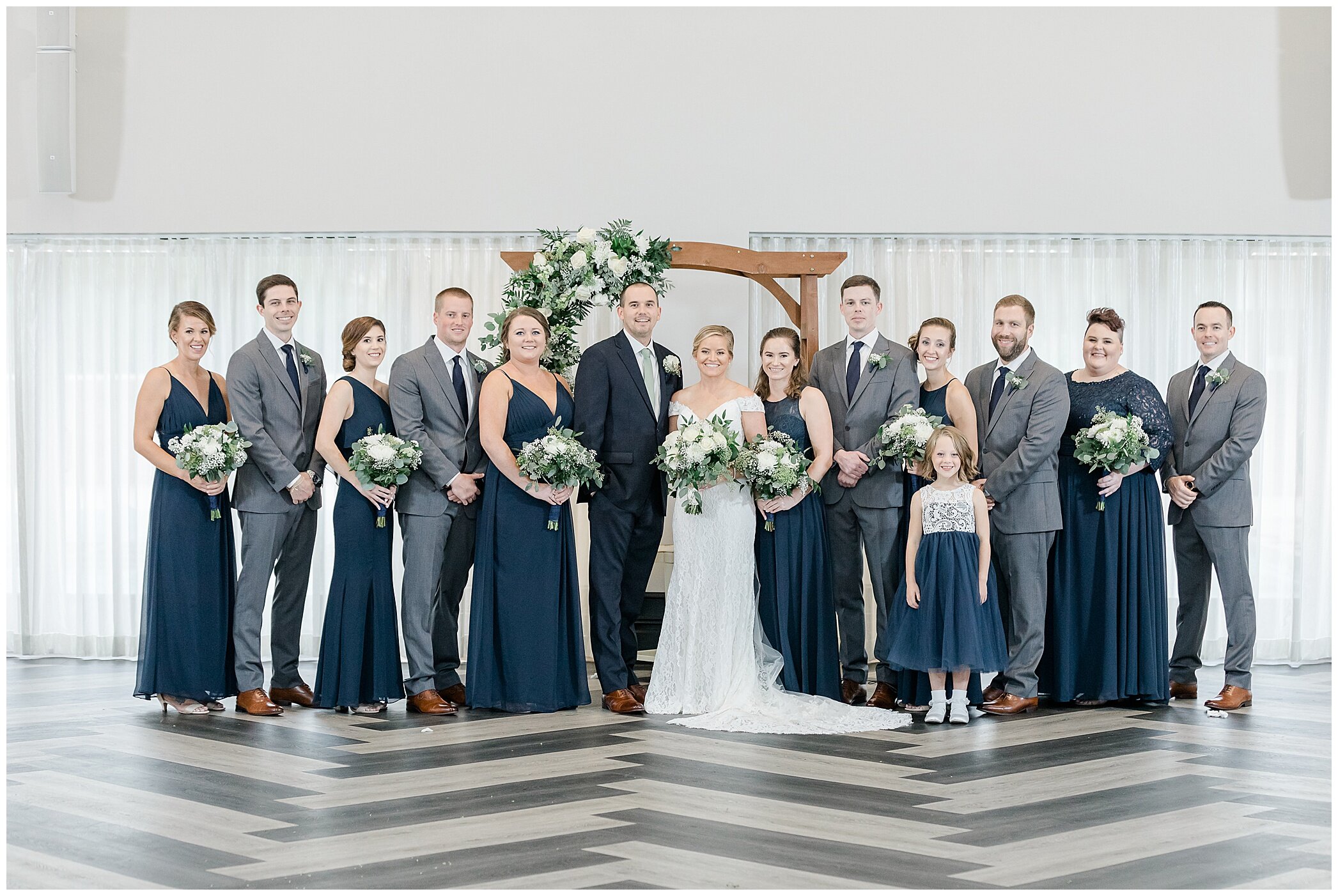 bride and groom pose with bridal party in navy and grey