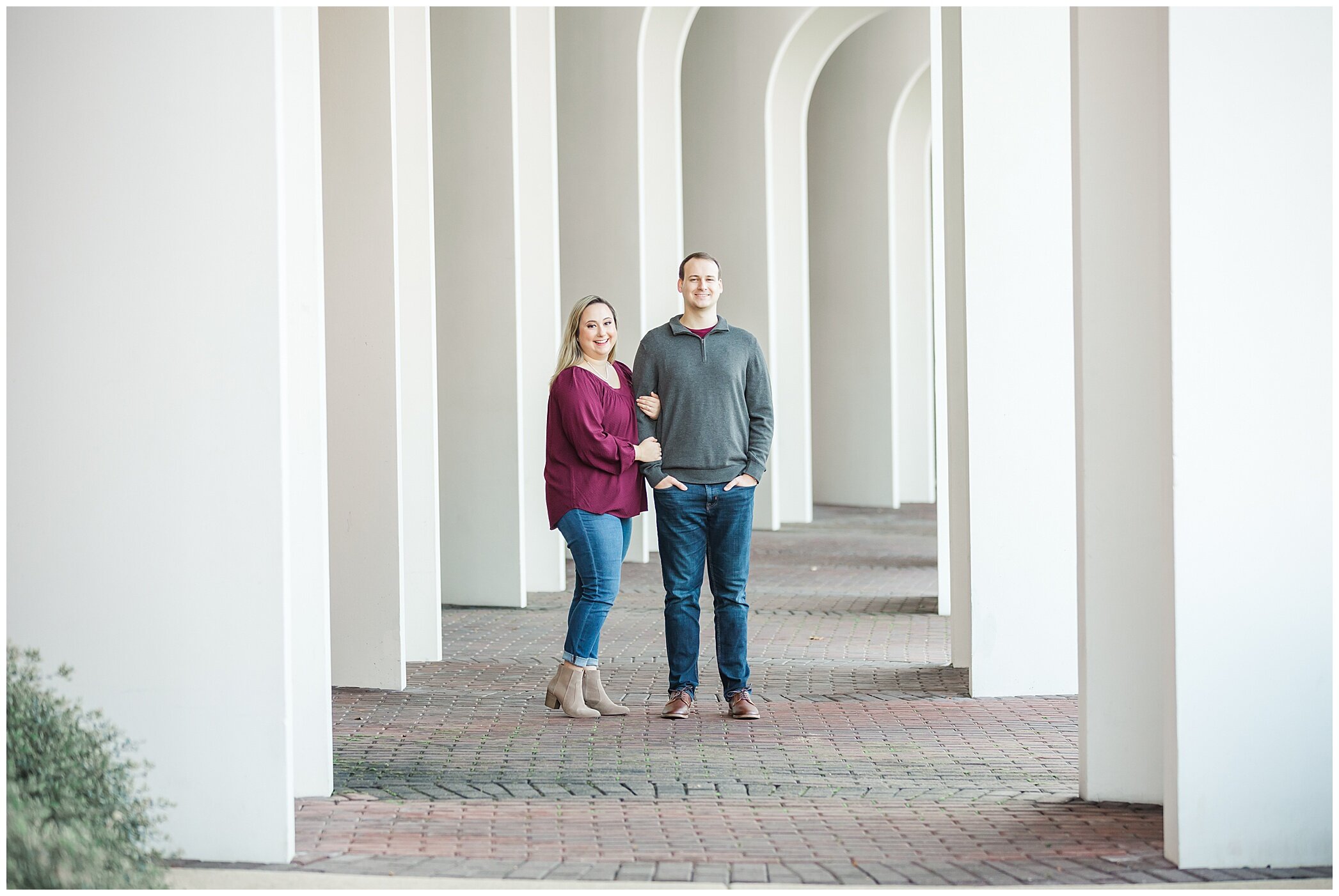 engaged couple poses under white arches at Christopher Newport University