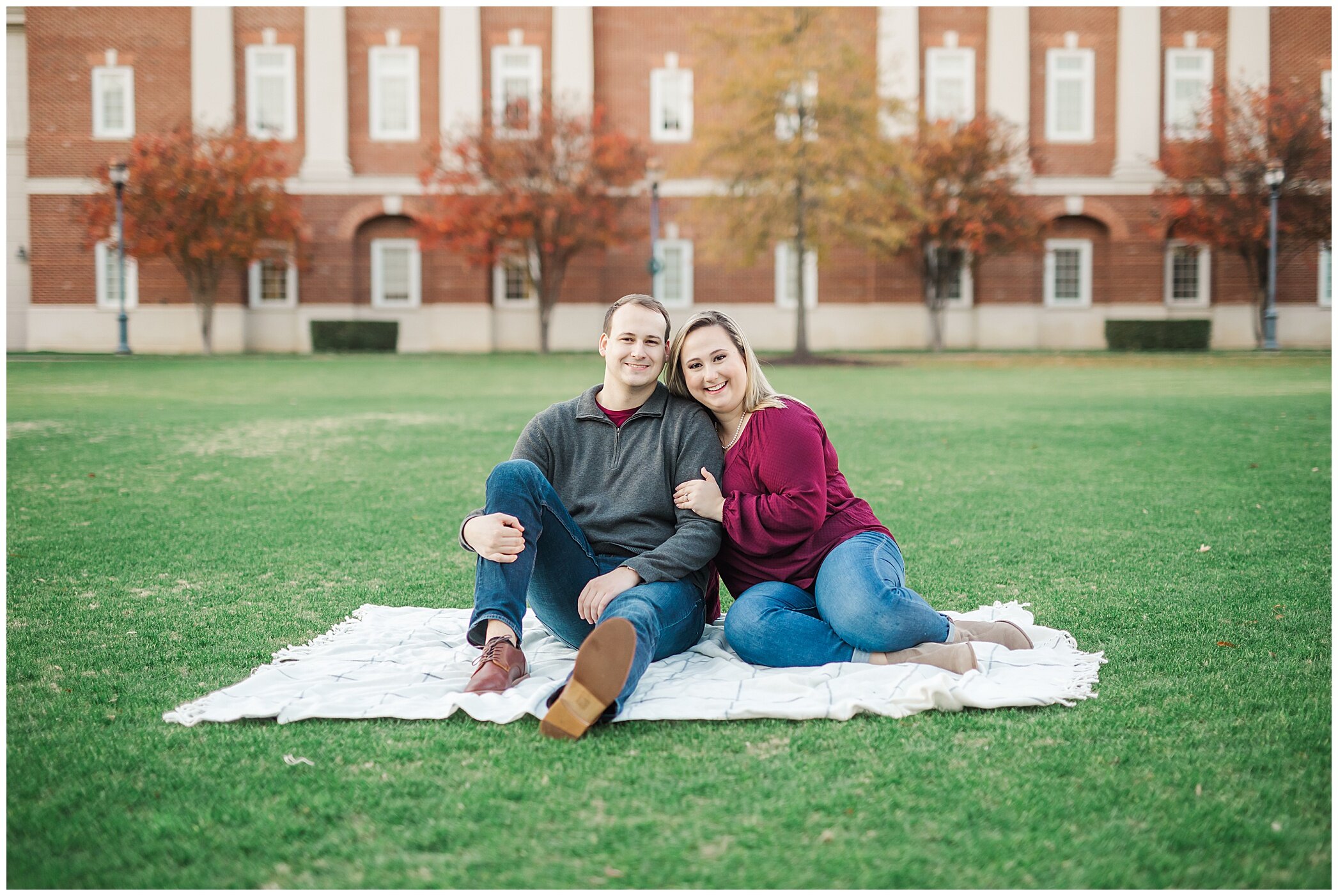 engaged couple sits on blanket on lawn at Christopher Newport University