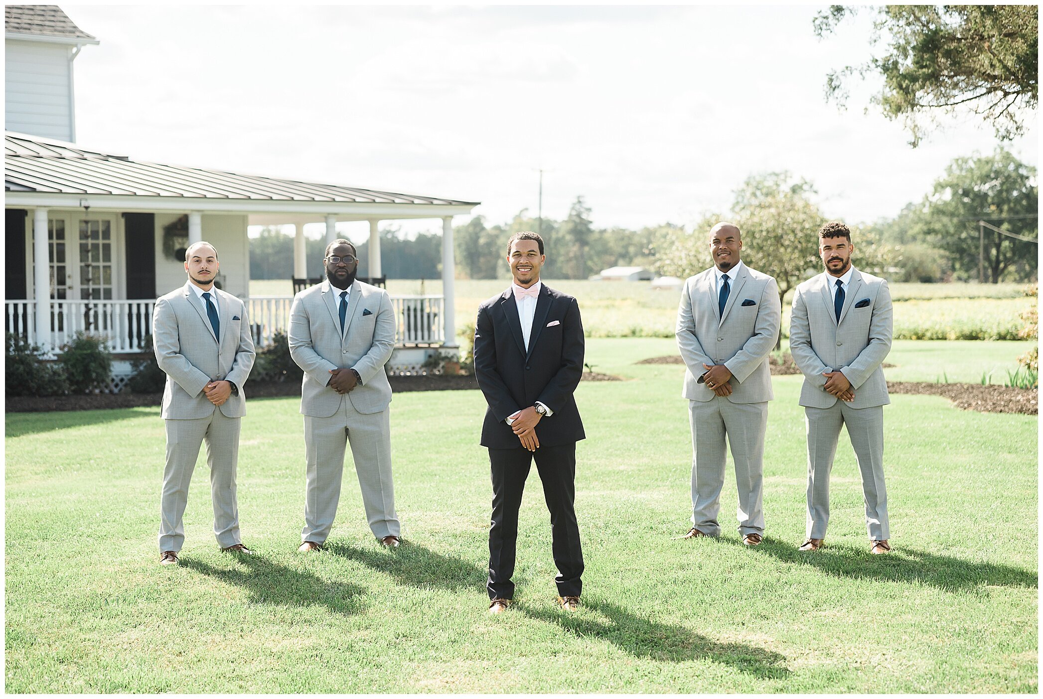 groom poses with groomsmen in grey suits at the Barns at Timberneck