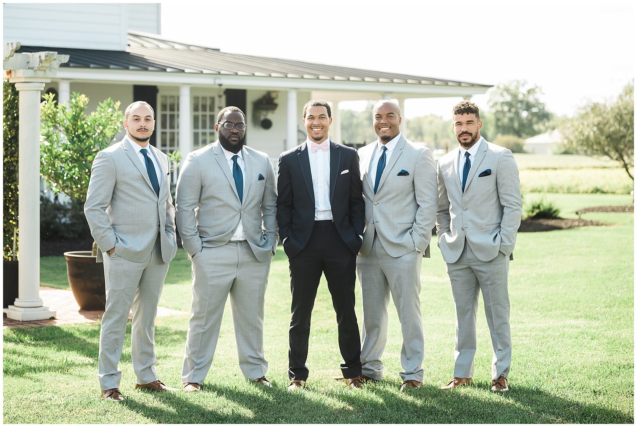 groom in navy suit poses with four groomsmen in grey suits