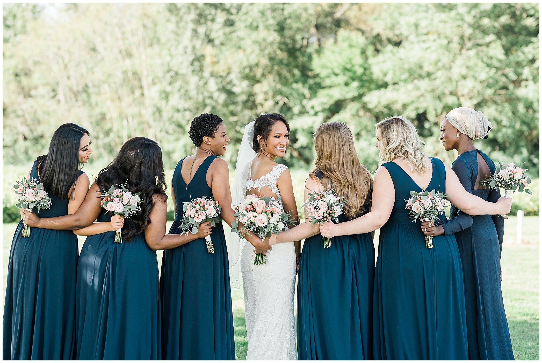 bride and bridesmaids look over shoulders at photographer
