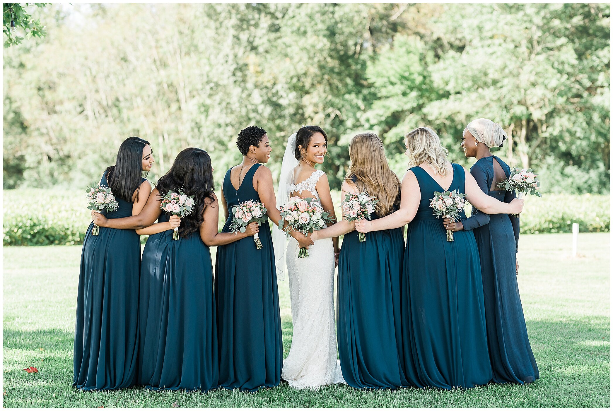 bride poses with six bridesmaids in teal gowns
